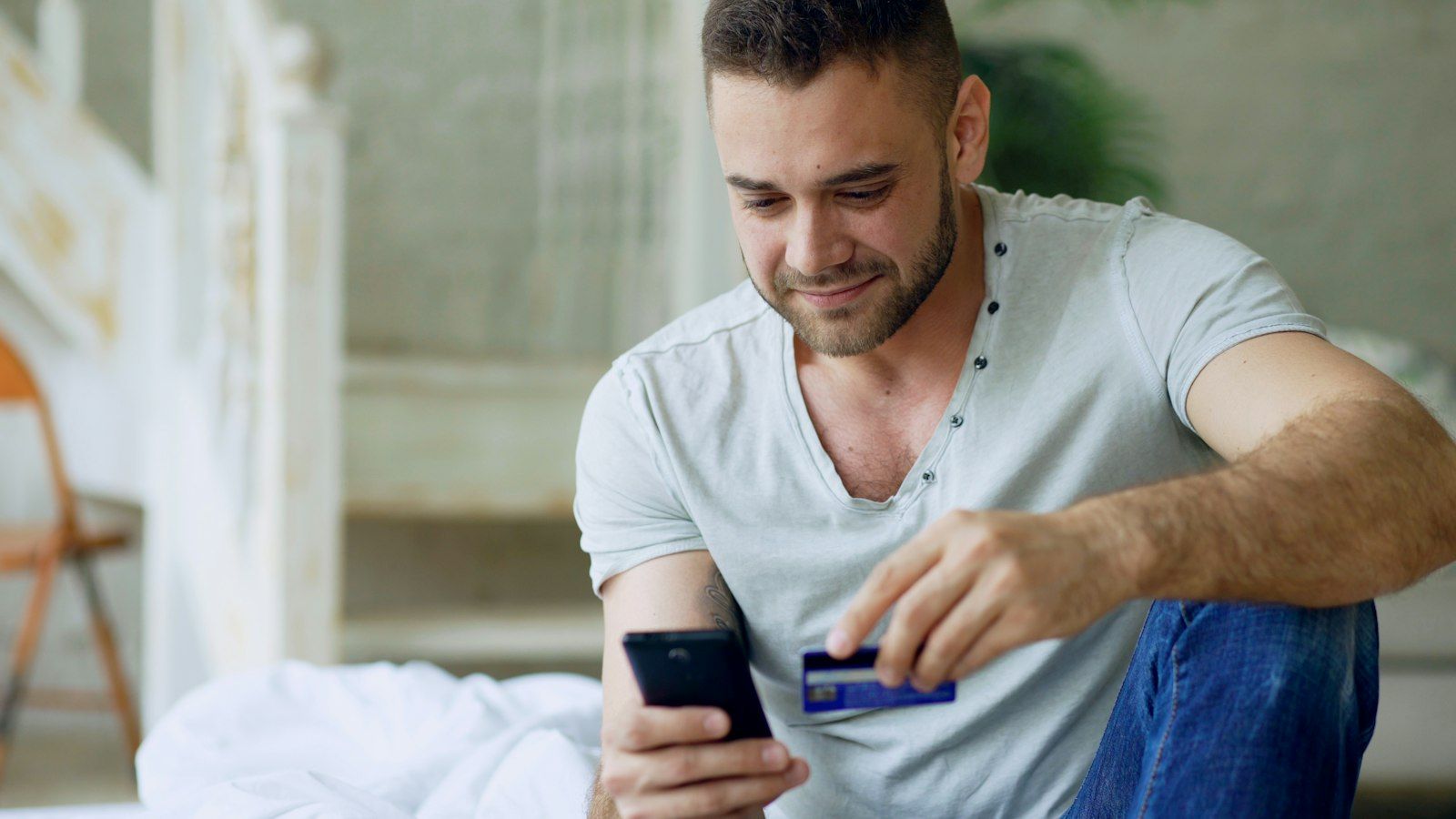 رجل يتسوق عبر الإنترنت من هاتفه الذكي ويحمل بطاقة دفع